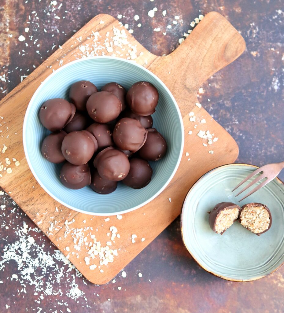 Gezondere Bounty balletjes met kokos, chocolade, havermout, dadels en noten in een kom van bovenaf (low FODMAP, glutenvrij, lactosevrij)